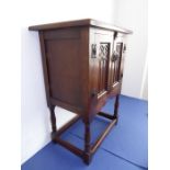 A good reproduction oak side cabinet; the overhanging top above two panelled doors decorated with