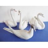 Four pieces of Lladro porcelain; a matched pair of swans (approx. 22cm high), another swan furling