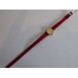 A lady's circular Omega De Ville automatic wristwatch; the gold-coloured dial with baton markers, on