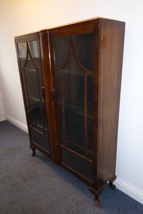 A 1920s/1930s two-door walnut display cabinet; pagoda-style astragal glazing bars and raised on