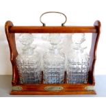 A late 19th / early 20th century oak-cased three-bottle tantalus; silver-plate mounts worn, locked