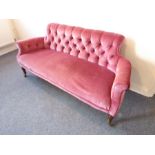 A late 19th / early 20th century pink velour upholstered button-back sofa; turned slightly
