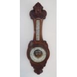 A late 19th century carved oak aneroid barometer; the cresting carved with central scallop-shell