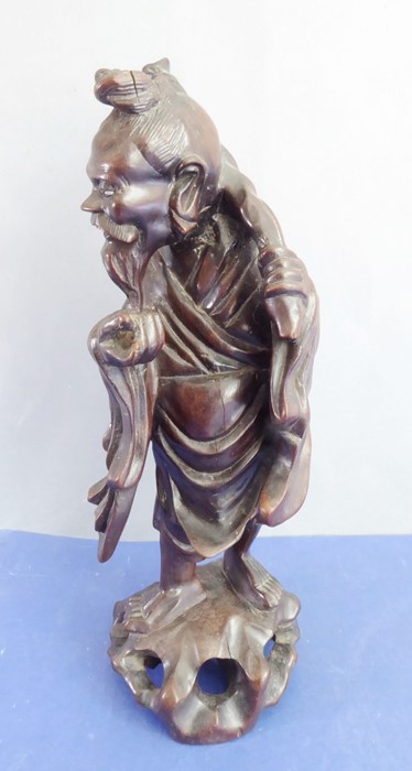 A late 19th century well patinated Chinese hardwood carving of a smiling fisherman (small crack to