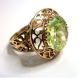 An ornate dress ring, centrally set with a pale green stone above the openwork 'S' scroll surround