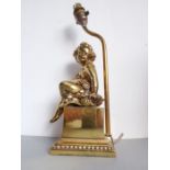 A modern gilt-metal table lamp; modelled as a seated cherubic figure upon a plinth base (height to