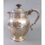 A hallmarked silver hot-water jug of ovoid form, Sheffied assay marks (rubbed), leaf-capped