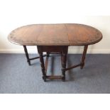 An antique oval oak drop-leaf gateleg table; the border decorated with incised lunettes, bulbous
