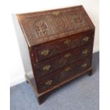 A late 18th century oak writing bureau; later carved with large lunettes and flowerhead designs in