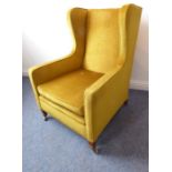 A mustard-coloured Draylon-upholstered armchair raised on square slightly tapering legs with brass