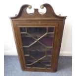 A George III hanging oak corner cupboard; the broken swan-neck pediment above 13-panel glazed door