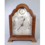 An early 20th century walnut-cased mantle clock; the arched dial with silvered chapter ring