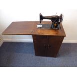 A Singer electric sewing machine housed within an Art Deco style and period oak cabinet (53cm wide x