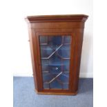 A late 18th century hanging mahogany corner cupboard, the large outset cornice above a single 13-
