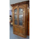 A mid-18th century freestanding oak corner cupboard; two arched glazed doors enclosing shaped