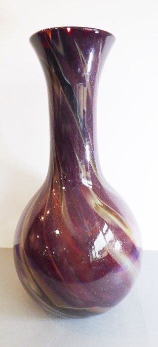 An oversized glass bottle vase decorated with brown, red and green multi-colour swirls and with