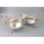 A matched pair of hallmarked silver sauceboats of thick gauge; each with high leaf-capped