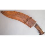 A Gurkha kukri with patinated wooden handle; the brown leather scabbard without the karda and