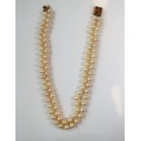 A two-row cultured pearl necklace with gem-set clasp; the cultured pearls measuring 8mm in diameter,