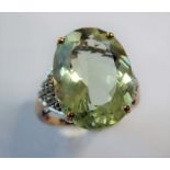 A pale green (probably beryl) ring, the oval mixed-cut stone claw-set to the 9 carat yellow and