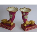 A pair of 19th century hand gilded and decorated porcelain cornucopia; ram's head terminals above