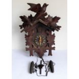 A mid-20th century carved Swiss or Black Forest cuckoo clock with pediment, pendulum and pinecone-