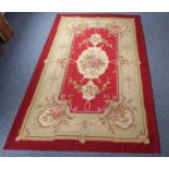 An Aubusson wall-hanging tapestry with a central floral motif and crimson border decorated with