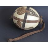 An early to mid-20th century ostrich egg; decorated in relief with hand-cut leather appliques,