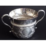 A two-handled loving cup; in late 17th century style, elaborate cartouche with foliate repoussé