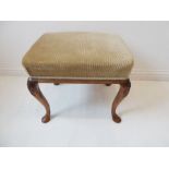 A 19th century walnut stool in 18th century style; the overstuffed top above four cabriole legs