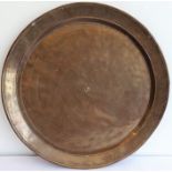A large patinated circular bronze dish/charger, 18th/19th century; with raised lip and angular sides