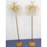 A pair of mid-20th century brass floor standing lamp standards; each with curved supports and