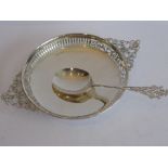 A circular silver bowl with pierced border and pierced upward turning handles; raised on short