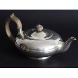 A hallmarked silver teapot of squat baluster form; carved wooden handle and raised on circular foot,