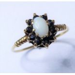 A cabochon opal and sapphire-set cluster ring to the 9 carat yellow gold ornate shoulders and