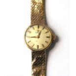 A lady's 9-carat yellow-gold wristwatch by Omega; the champagne-coloured dial with baton markers