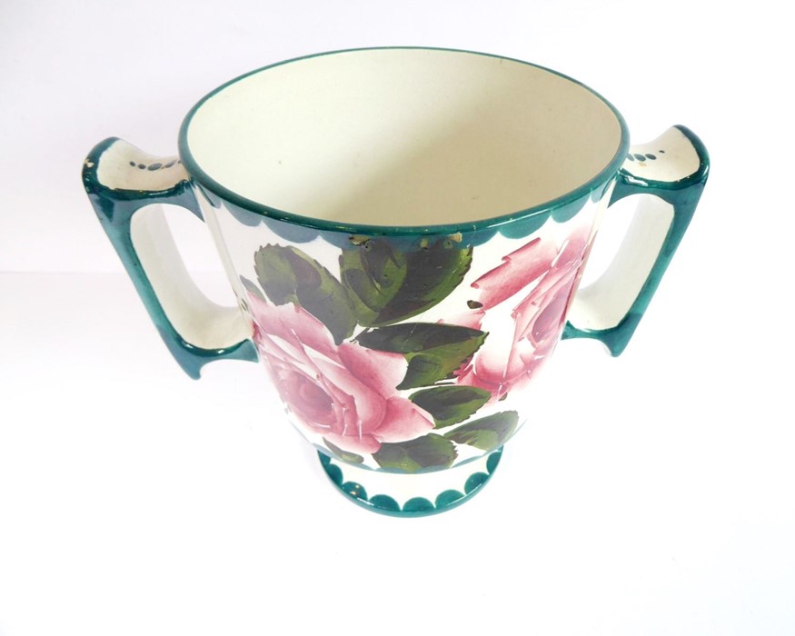 An early 20th century two-handled Wemyss Pottery loving cup; hand-decorated with roses, stamped