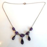 A lady's silver necklace set with hand-cut oval stones of amethyst colour and with three pear-shaped