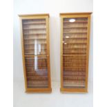 A pair of pine display cabinets with single glazed doors (102cm tall x 14cm deep x 57cm wide) (2)