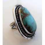 A large custom-made silver ring centrally set with a pear-shaped polished turquoise cabochon