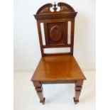 A late 19th century oak hall chair; the central panel carved with a single sunflower in the