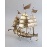 A small Chinese silver model of a junk; with moveable rudder, single figure on deck with two cannons