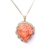 A coral and diamond-set pendant, the coral centre carved to depict the head of a maiden with flowers