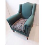 An early 20th century British racing green upholstered armchair; raised on square tapering legs with