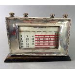 An early 20th century hallmarked silver-fronted perpetual desk calendar; the silver frame