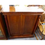 A mid-19th century mahogany side cabinet; two panelled doors enclosing shelves and flanked by turned