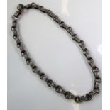 A long and ornate silver chain necklace; round rings linking pierced filigrees-style oval links,