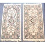 A pair of cream ground rugs (each 134cm x 71cm)