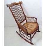 A late 19th century American-style walnut rocking chair; comb-style back above a rattan-cane seat