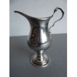 A hallmarked silver cream jug of late 18th century-style; baluster-shaped body above a circular